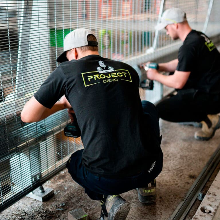 Demolition crew members installing protective screens at a work site.